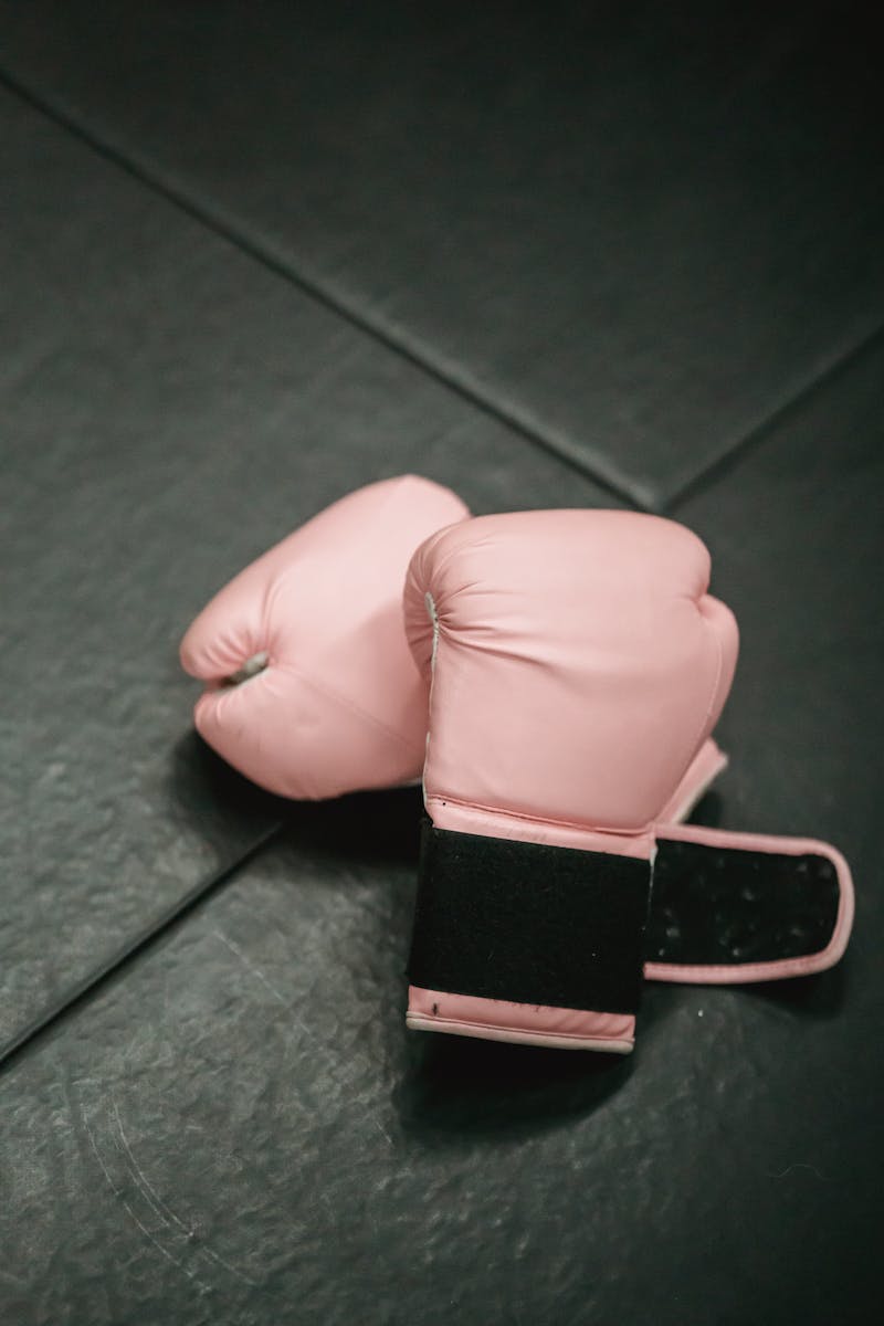 Overhead shot of pink boxing gloves on black gym mat. Ideal for fitness and sports concepts.