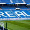 Empty seating area in Real Madrid's stadium with 'REAL' prominently displayed in white.
