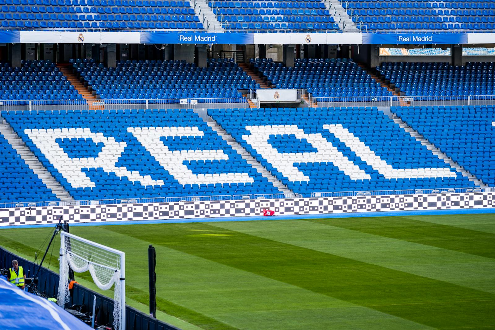 Empty seating area in Real Madrid's stadium with 'REAL' prominently displayed in white.