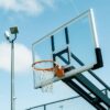 Outdoor basketball hoop with backboard under a clear blue sky, perfect for sports and recreation themes.
