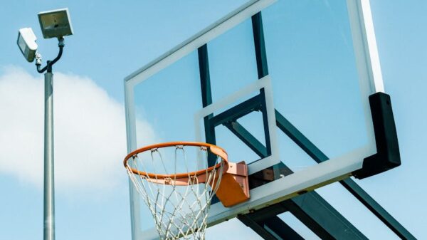 Outdoor basketball hoop with backboard under a clear blue sky, perfect for sports and recreation themes.