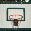 A rustic basketball hoop with a weathered backboard outdoors.