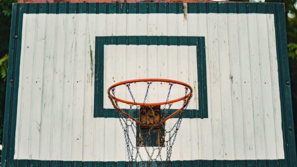 A rustic basketball hoop with a weathered backboard outdoors.