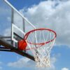 A basketball hoop and backboard set against a clear blue sky, capturing the essence of outdoor sports.