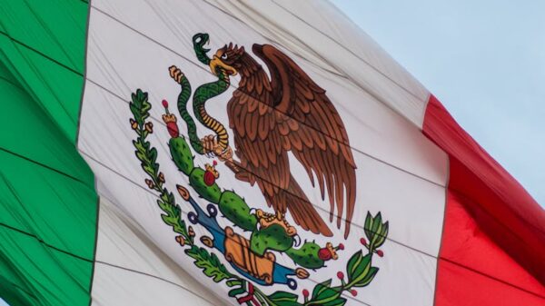 Brightly colored Mexican flag waving against a clear blue sky, symbolizing patriotism and freedom.