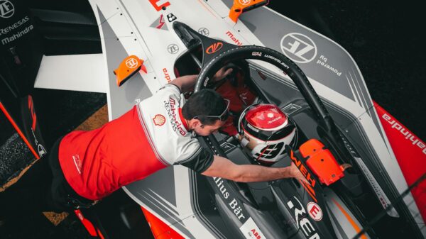 Top-down view of Formula E driver with crew member at Ciudad de México track, showcasing teamwork and technology.