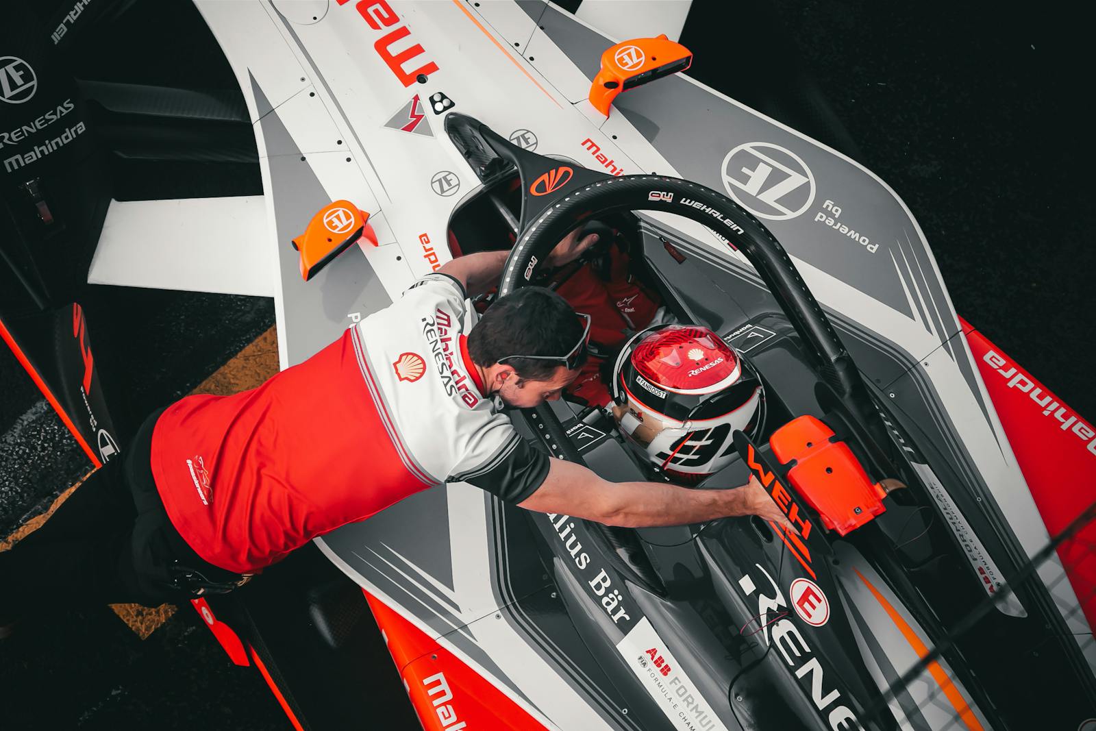 Top-down view of Formula E driver with crew member at Ciudad de México track, showcasing teamwork and technology.