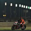 Motorcycle racer in action on the track at night, showcasing speed and skill under stadium lights.