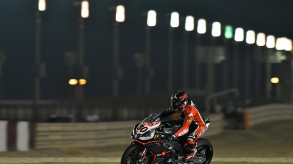 Motorcycle racer in action on the track at night, showcasing speed and skill under stadium lights.