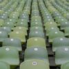 Close-up view of empty green stadium seats with numbered labels, in neat rows.