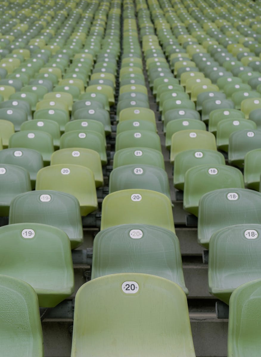 Close-up view of empty green stadium seats with numbered labels, in neat rows.