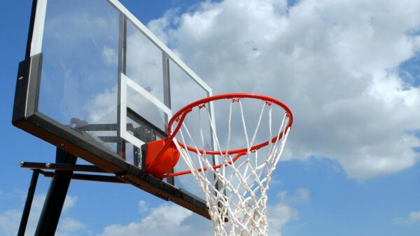 A basketball hoop and backboard set against a clear blue sky, capturing the essence of outdoor sports.