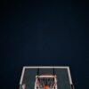 A basketball hoop silhouetted against a dark night sky filled with stars.