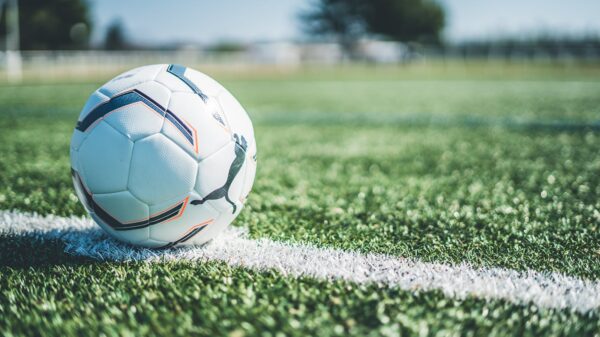 Soccer ball resting on white line of a green grass field. Perfect for sport themes.