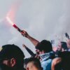 Passionate football crowd with flares and cheering, encapsulating excitement.
