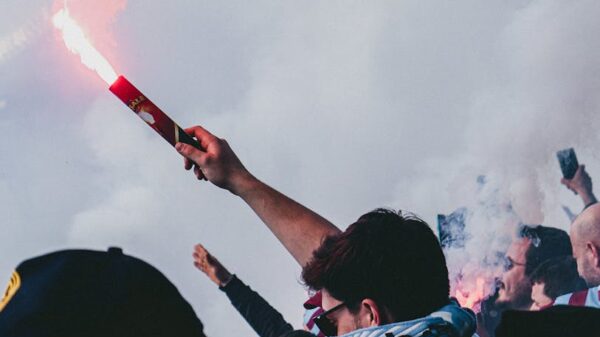 Passionate football crowd with flares and cheering, encapsulating excitement.