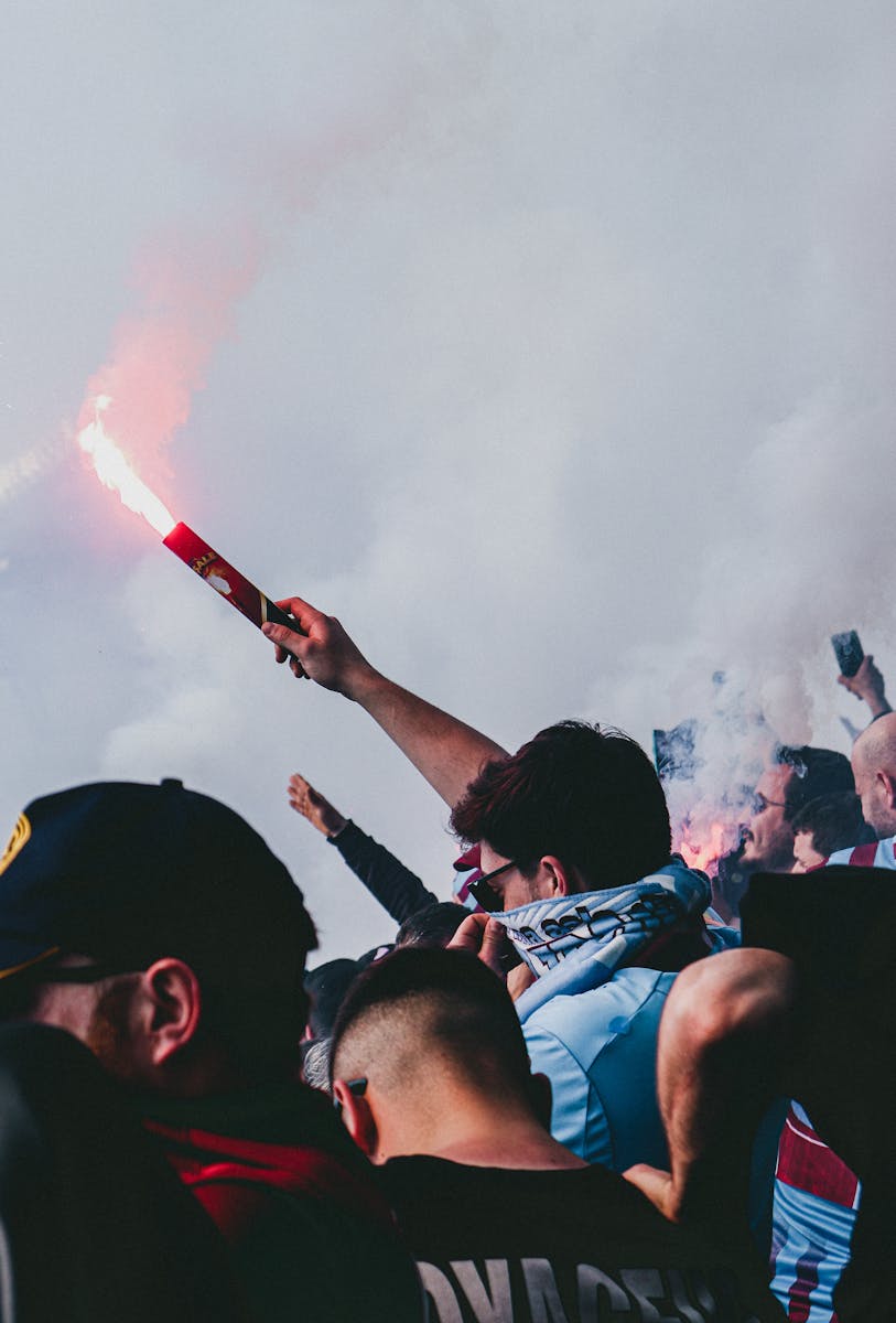 Passionate football crowd with flares and cheering, encapsulating excitement.