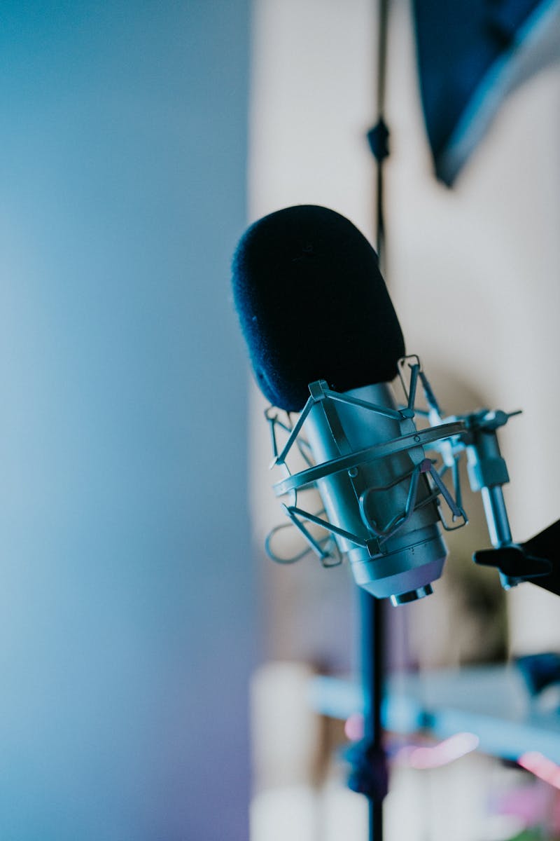 Close-up of a studio microphone with a blue backdrop, ideal for podcasts or recording.