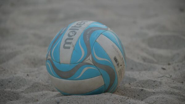 A close-up of a colorful beach volleyball resting on sand.