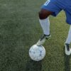 Close-up of a player controlling a soccer ball on a grass field.