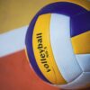 Colorful volleyball on an indoor court with visible lines, showcasing sports equipment.