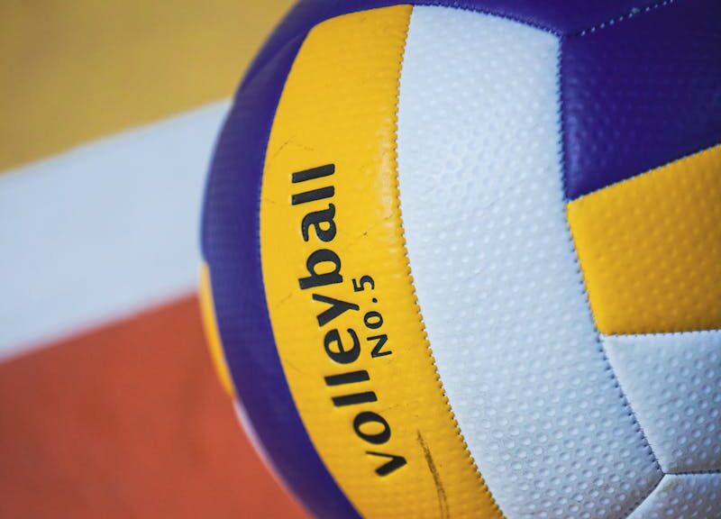 Colorful volleyball on an indoor court with visible lines, showcasing sports equipment.