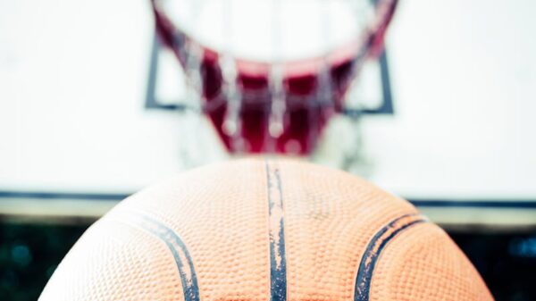 Vivid image of a basketball aiming for a hoop outdoors in daylight.