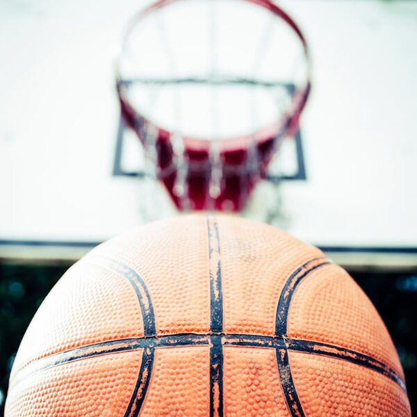 Vivid image of a basketball aiming for a hoop outdoors in daylight.