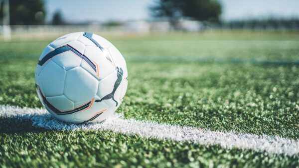 Soccer ball resting on white line of a green grass field. Perfect for sport themes.