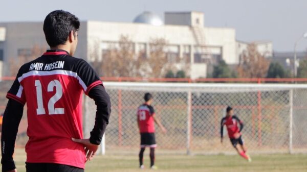 man in blue and red soccer jersey shirt and black shorts standing on green grass field