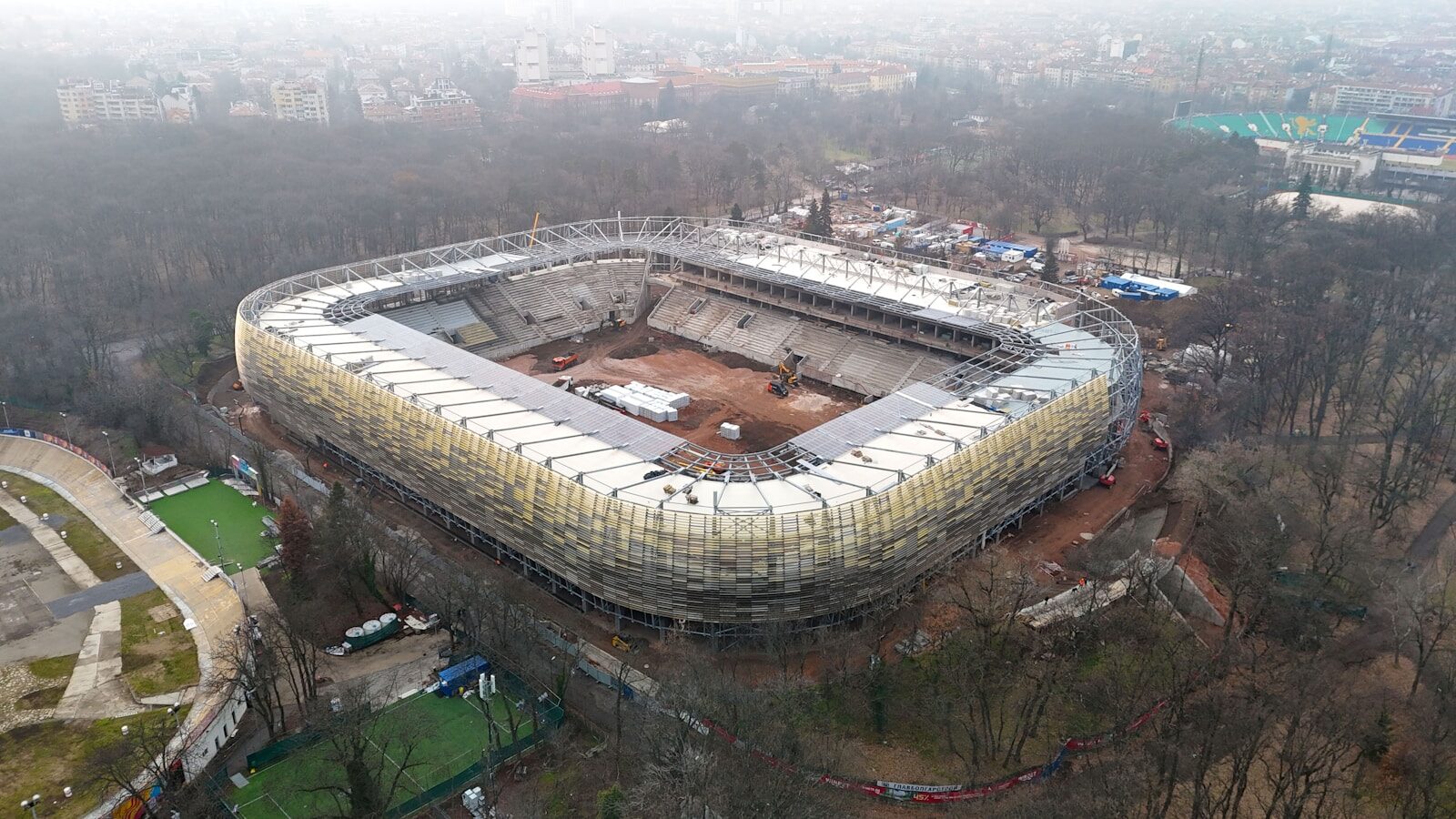 Aerial view of stadium under construction with surrounding trees