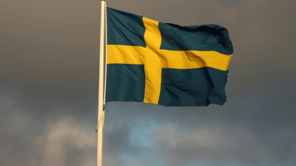 The Swedish flag waves on a flagpole in Jönköping, Sweden, framed by storm clouds.