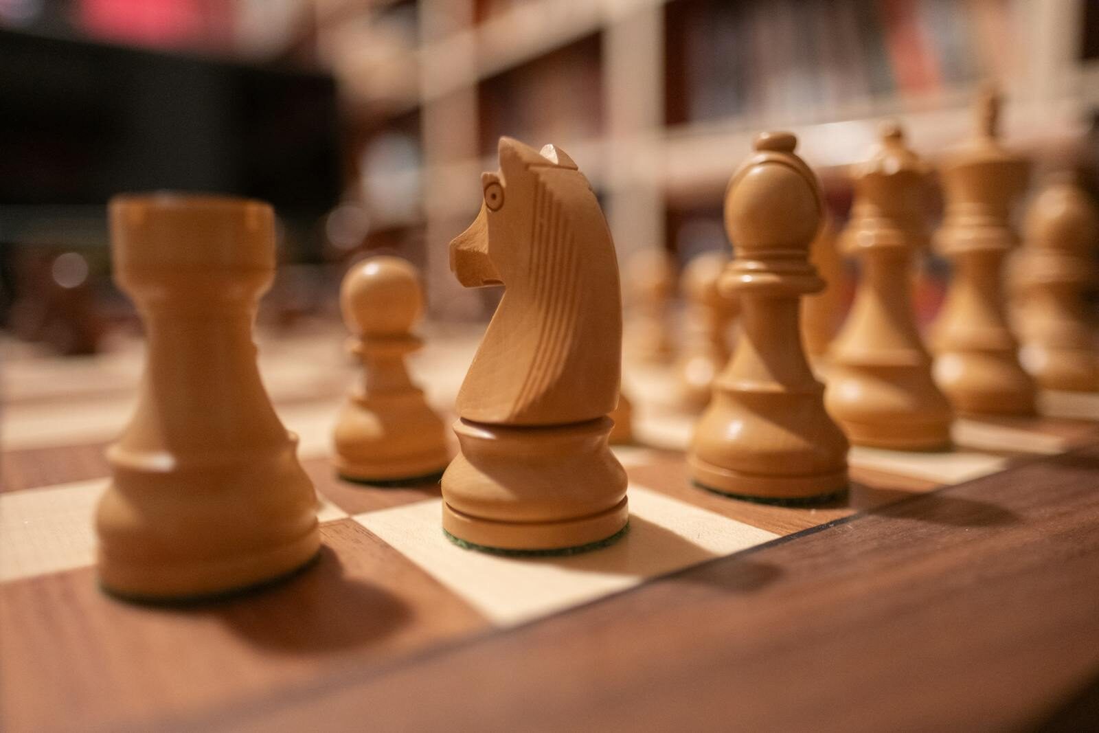 Focus on wooden chess pieces on a chessboard, creating a strategic atmosphere.