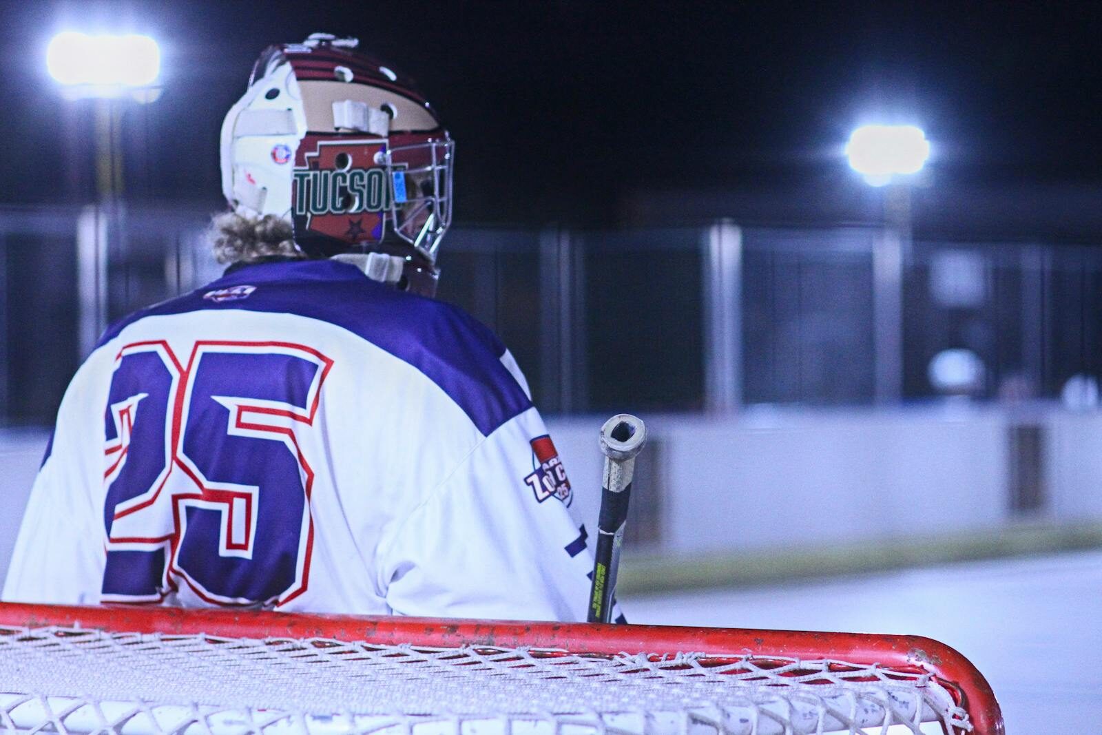 Exciting night roller hockey game in Tucson with player holding a stick.