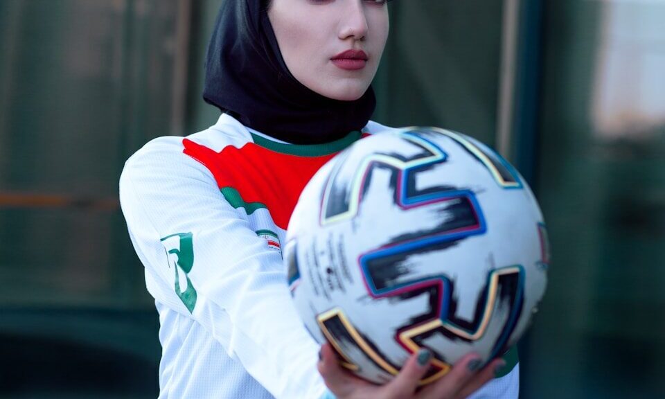 woman in white and blue long sleeve shirt holding white and black nike soccer ball