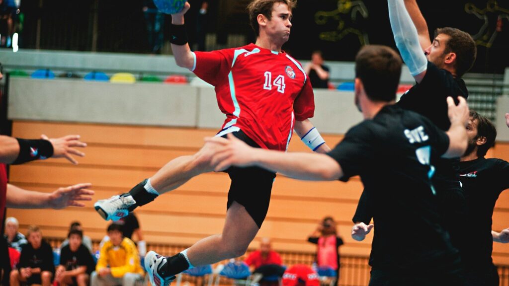 man holding ball while jumping near three mne