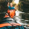 selective focus photography of woman riding kayak holding oar during daytime