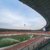 Wide-angle view of a modern stadium in Minsk with sprinklers on the field at dusk.