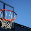 A vibrant outdoor basketball hoop with net set against a clear blue sky, ideal for sports visuals.