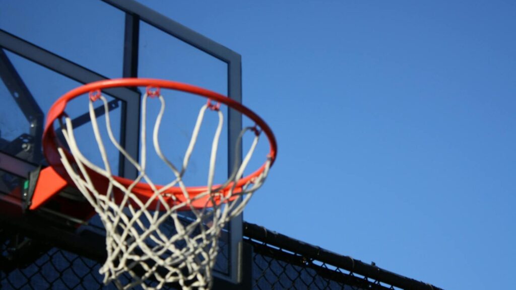 A vibrant outdoor basketball hoop with net set against a clear blue sky, ideal for sports visuals.