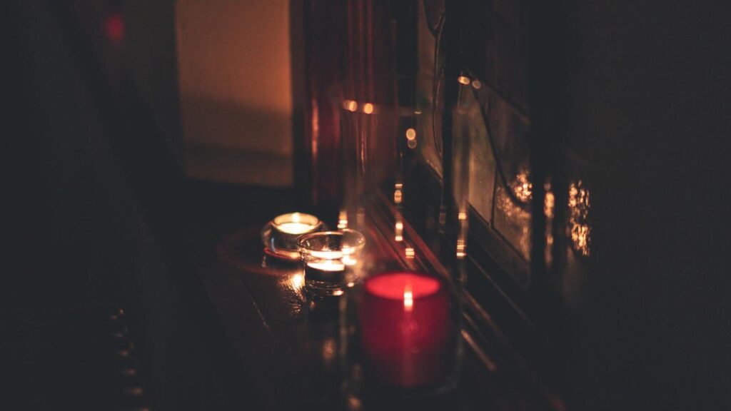 A close-up of candles illuminating a dark room with a warm, soft glow.