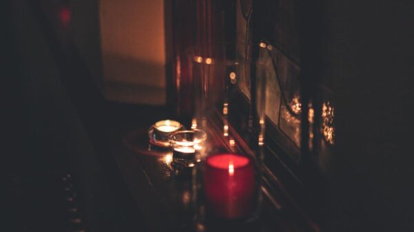 A close-up of candles illuminating a dark room with a warm, soft glow.