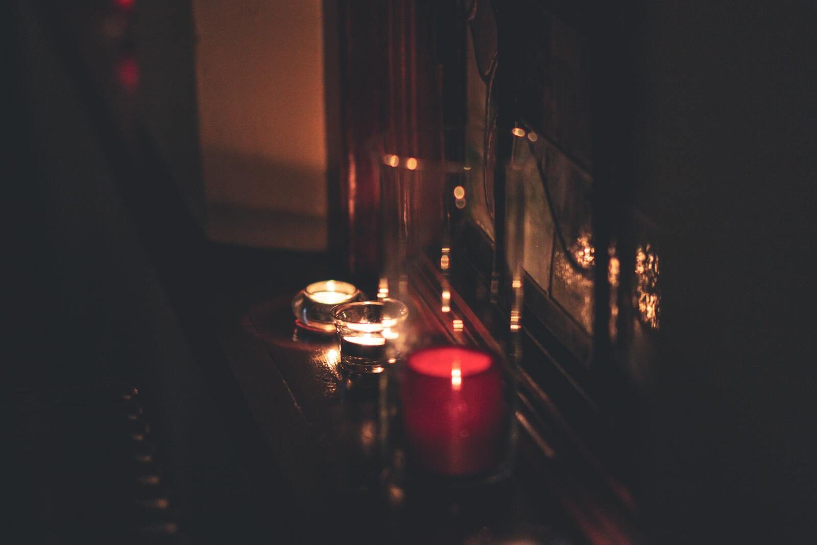 A close-up of candles illuminating a dark room with a warm, soft glow.