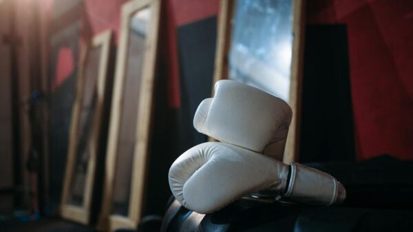 Close-up of white boxing gloves on gym equipment with mirrors reflecting in the background.
