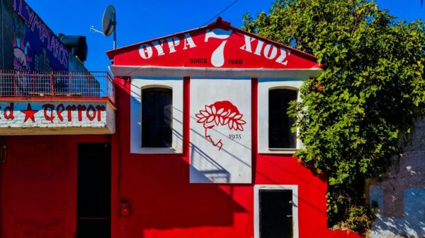 Colorful urban building in Chios with red facade and artistic mural under blue sky.