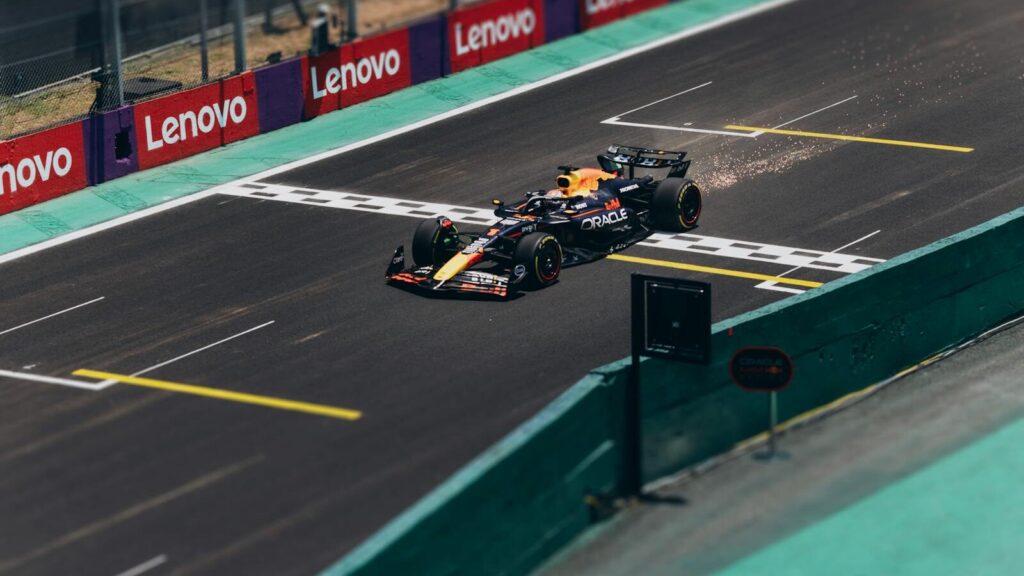 Formula 1 car speeding across the finish line on a racetrack, emitting sparks.