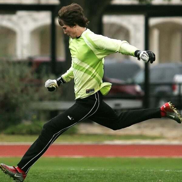 Dynamic shot of a soccer player in motion, kicking the ball on an outdoor field.