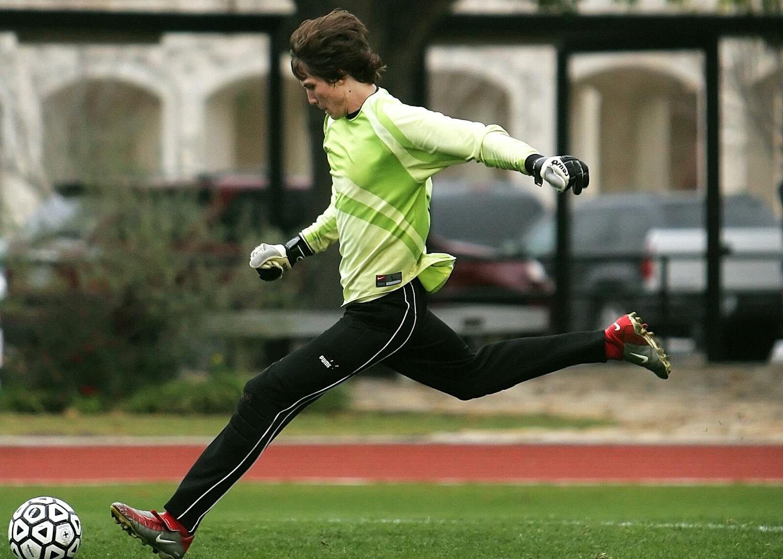 Dynamic shot of a soccer player in motion, kicking the ball on an outdoor field.