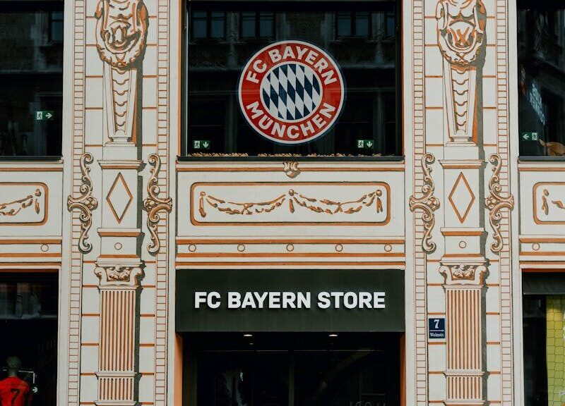 FC Bayern Store front in Munich showcasing the iconic Bayern Munich logo and architectural details.