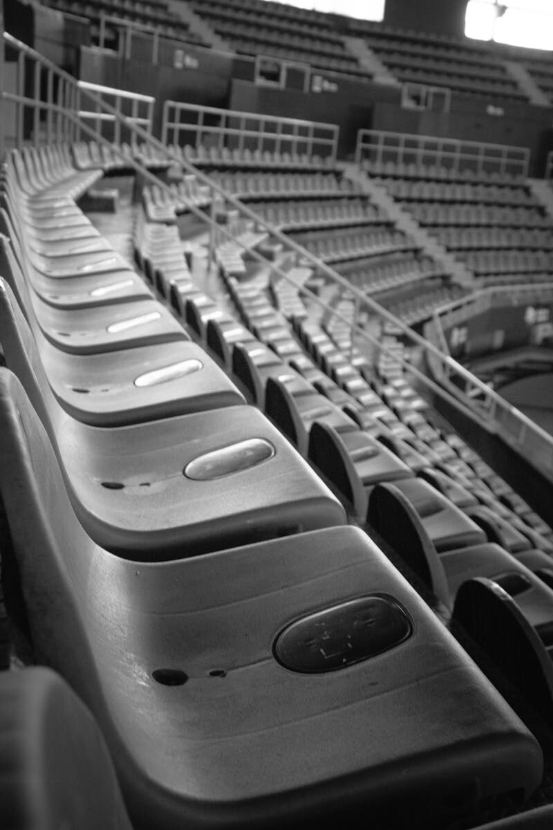 Black and white image of empty stadium seats with a focus on the symmetry and structure.
